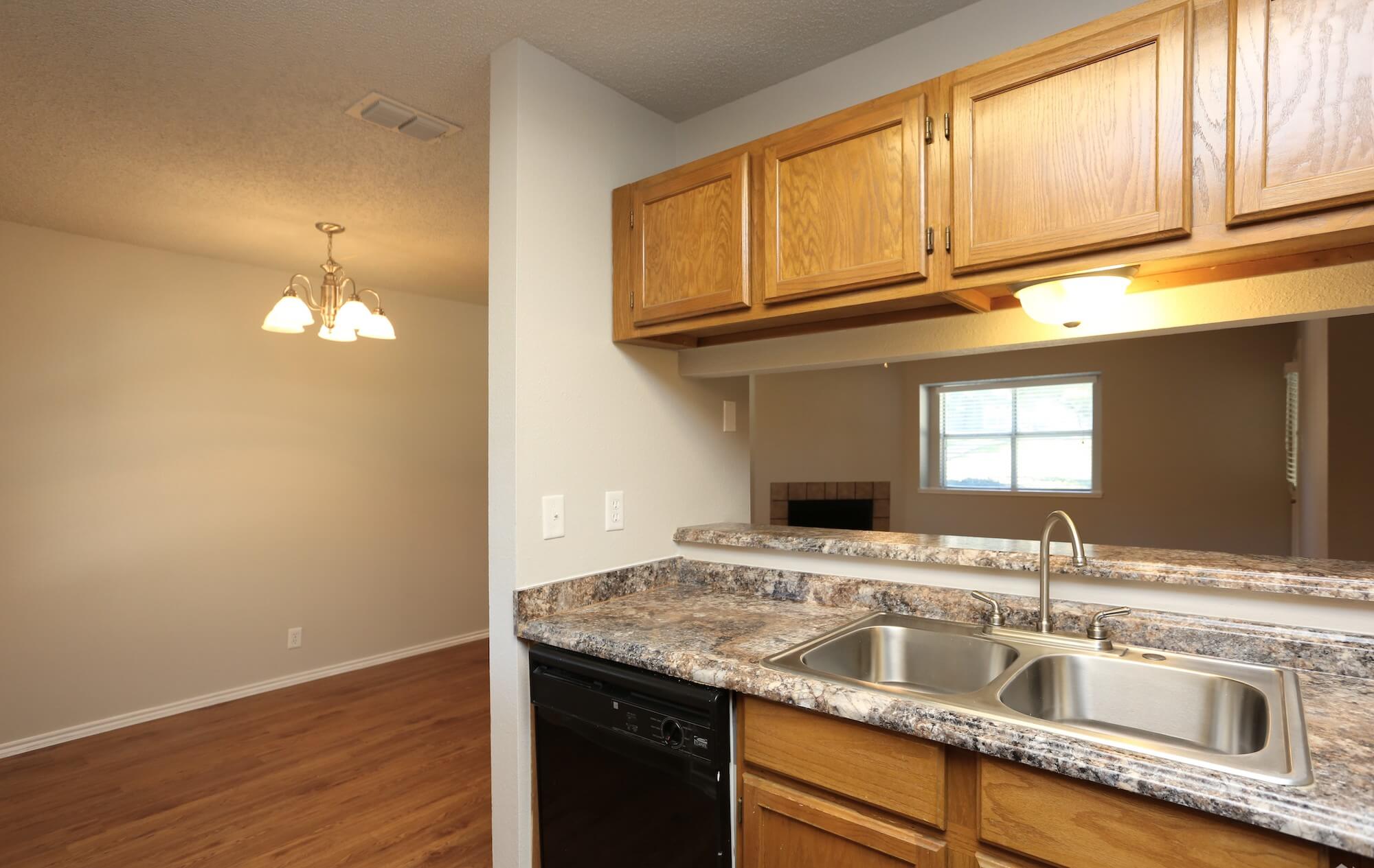 View from kitchen into living room showing additional overhead storage above sink.