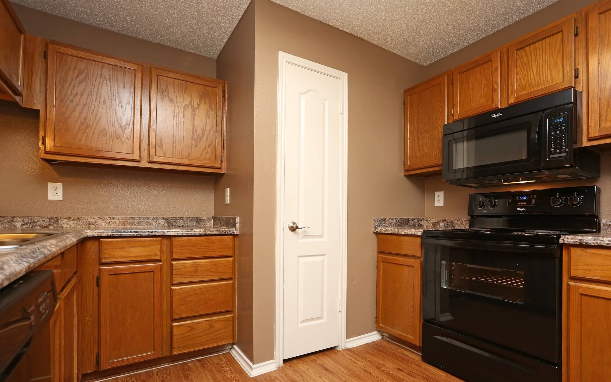 View of the kitchen with a stove, microwave, pantry, and plenty of cabinets.