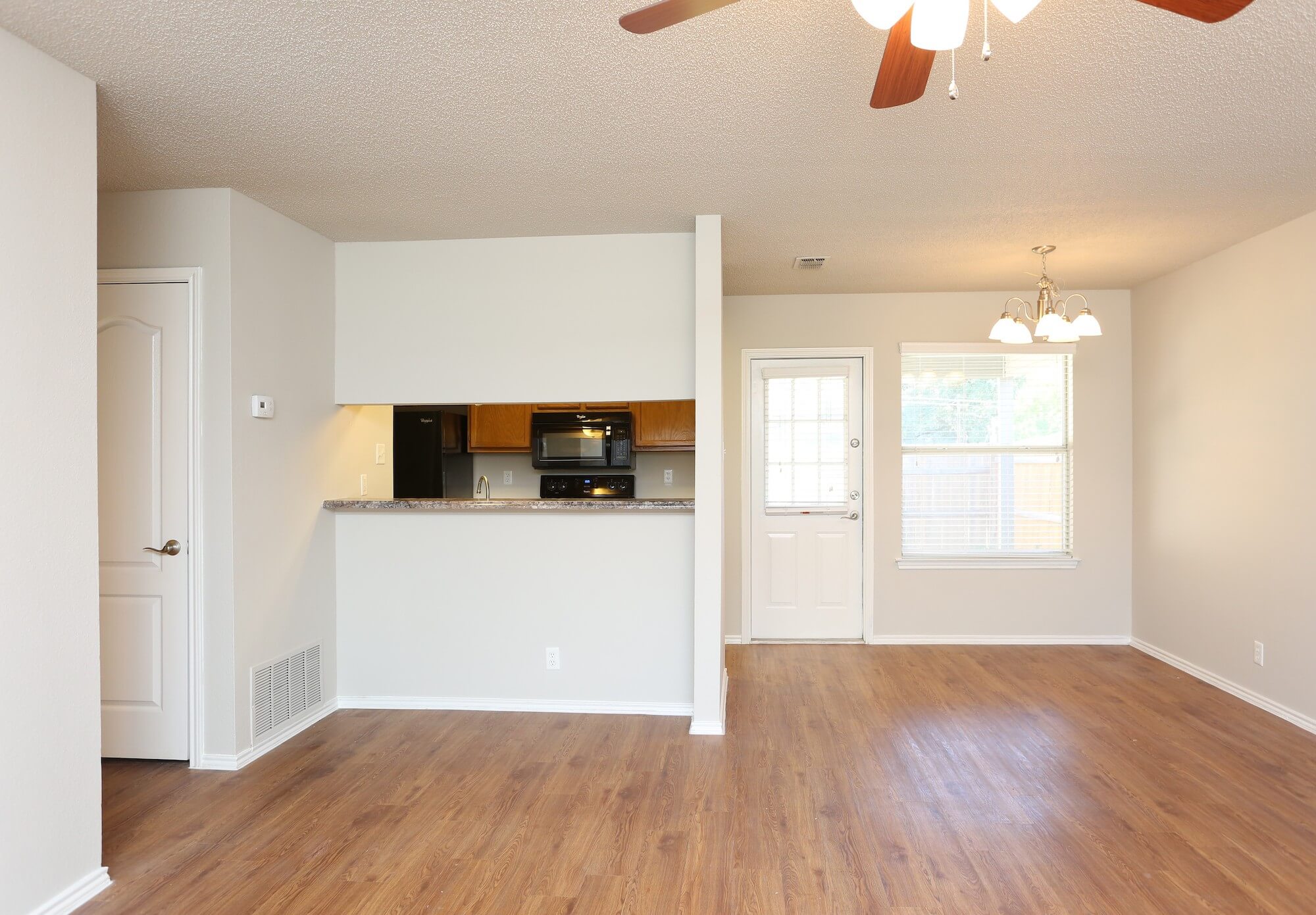 View from living room into kitchen with large windows and dining area.