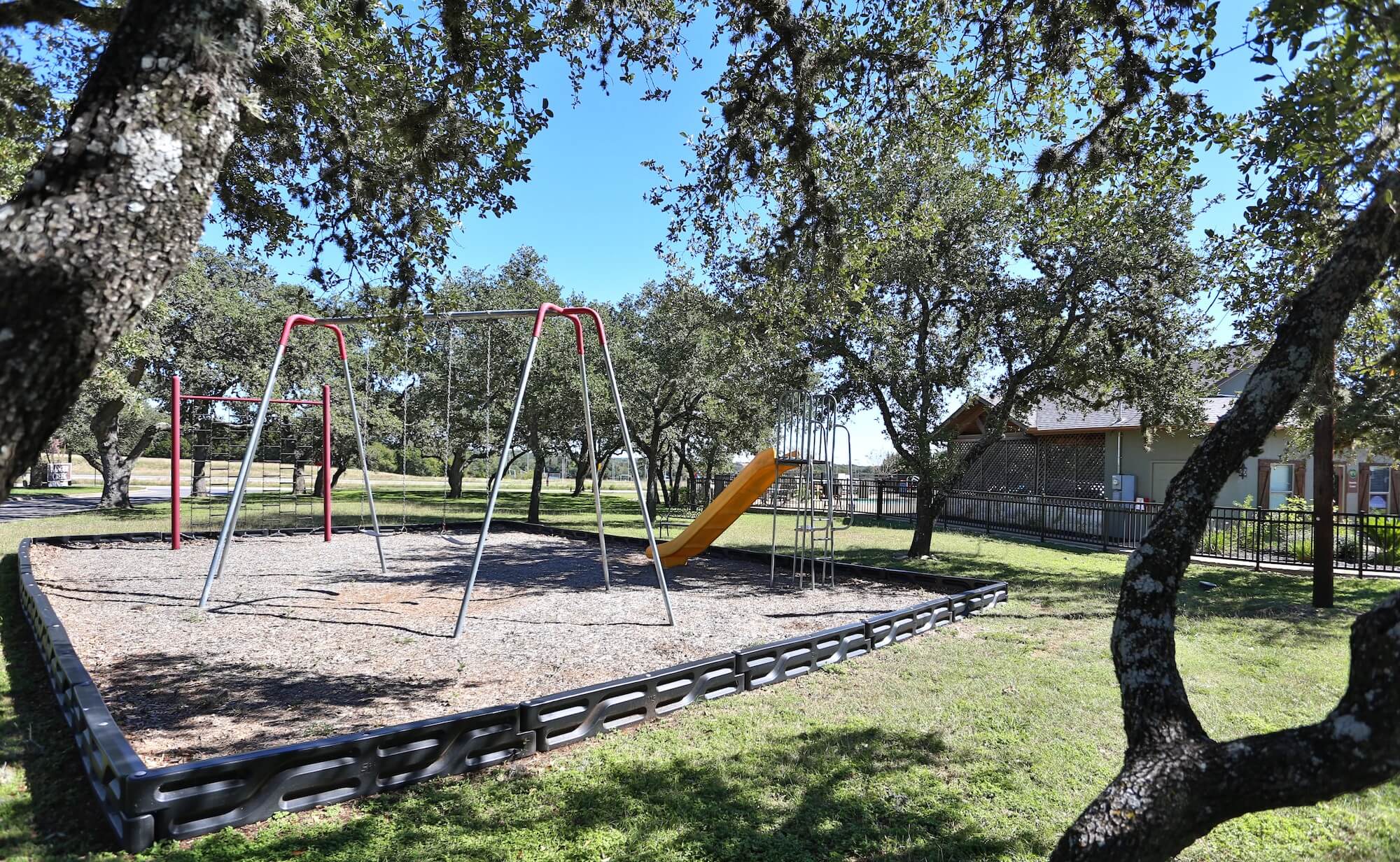 Playground equipment including swings, a slide, monkey bars, and more.