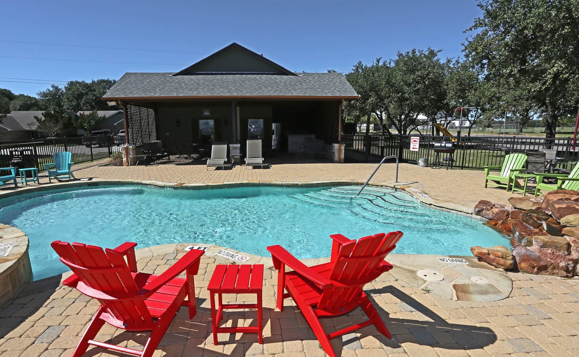 Community pool with two red chairs to lounge in